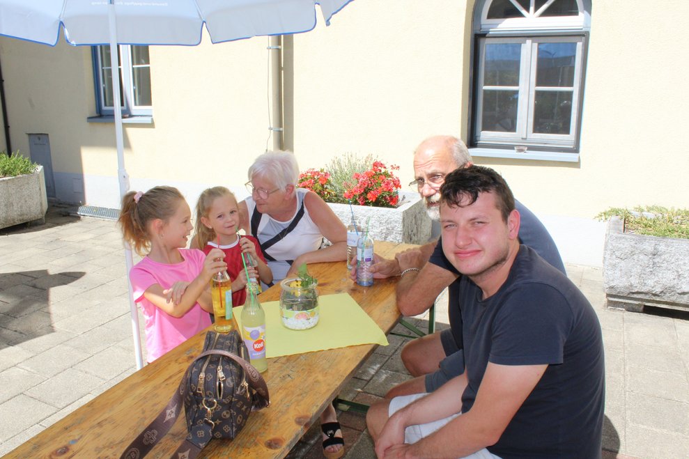 Erwachsenen und zwei Kinder sitzen bei einem Tisch.