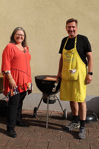 Eine Dame und ein Herr stehen bei einem Griller