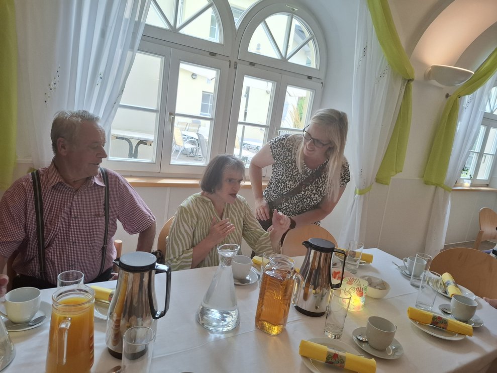 Drei Personen bei Kaffee und Kuchen.