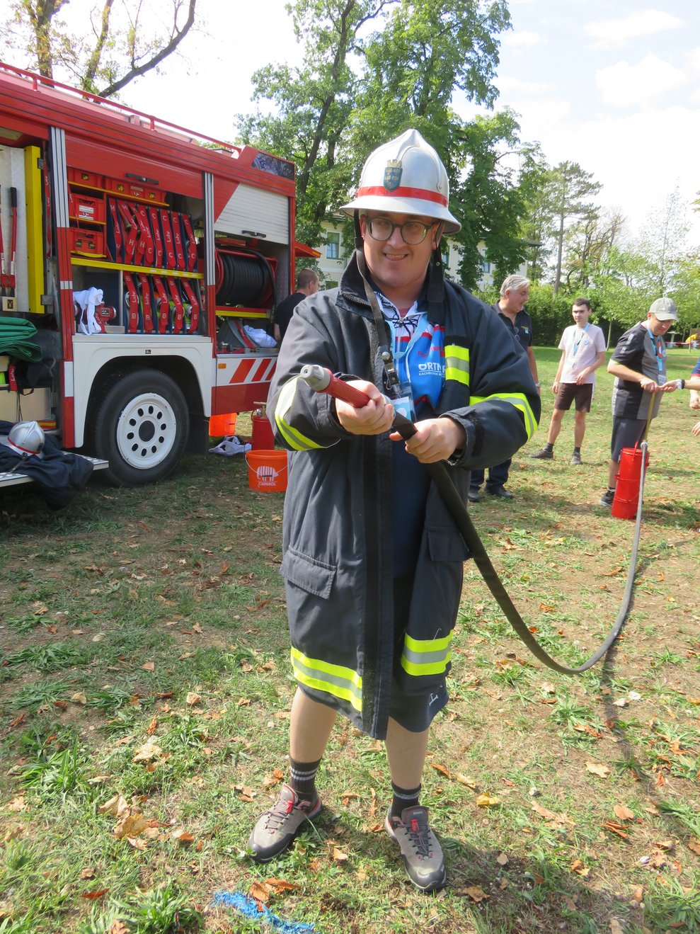 Ein Mann hat Feuerwehrgewand an und einen Schlauch in der Hand.