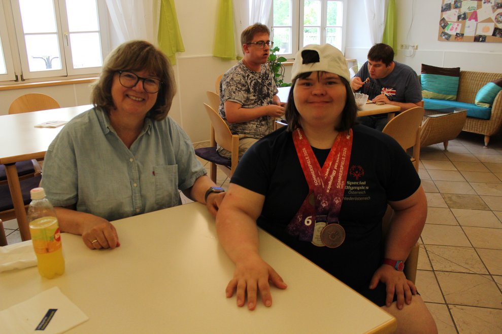 Zwei Damen sitzen beim Tisch.