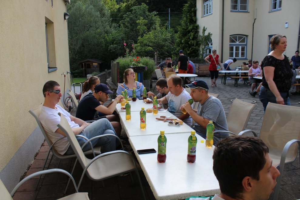 Mehrere Personen essen gemeinsam Grillwürstel, Grillkäse und Semmel.