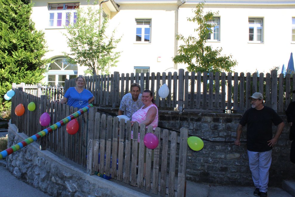 Vier Personen stehen auf einer Terrasse, neben viel Luftballons.
