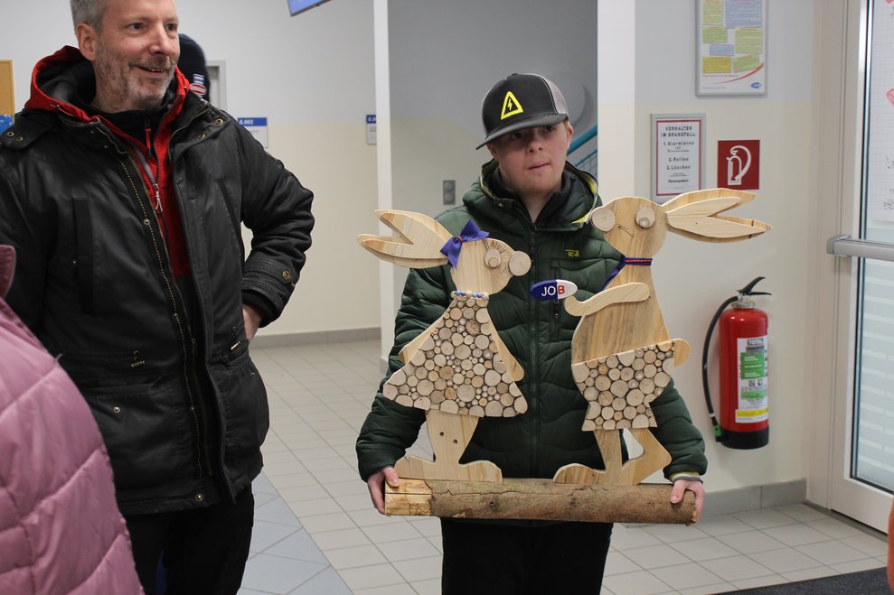 eine Person mit zwei Osterhasen aus Holz
