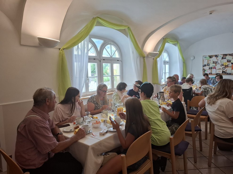 Mehrere Personen sitzen am Tisch bei Kaffee und Kuchen