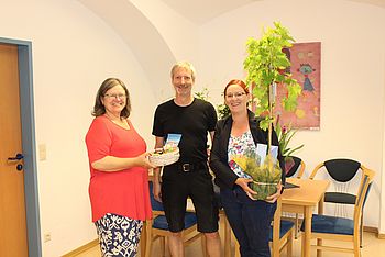 Zwei Personen überreichen ein Geschenk.