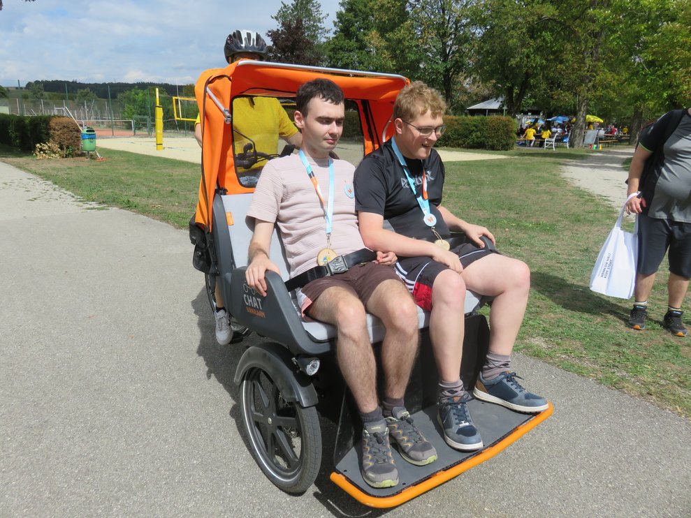 Zwei Männer fahren mit einer Rikscha mit.