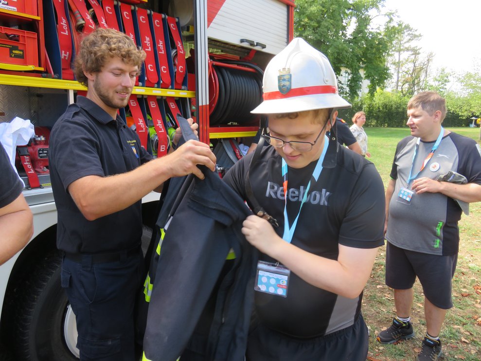 Ein Mann zieht eine Feuerwehr Jacke an.
