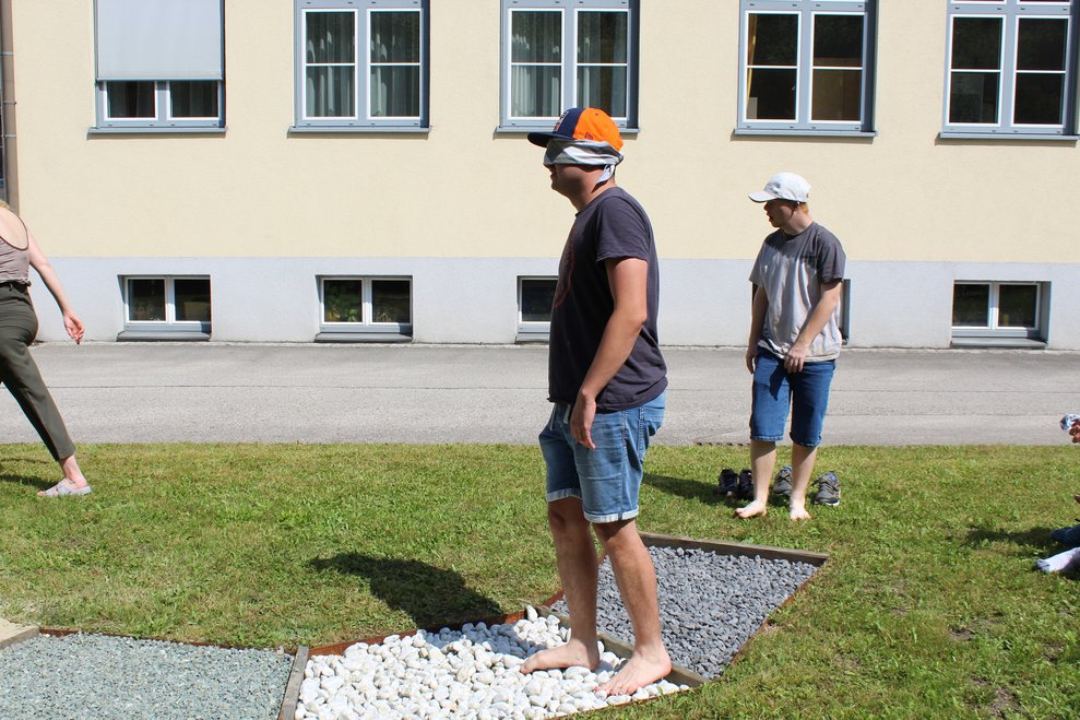 Eine Person geht mit verbundenen Augen über eine Barfußweg