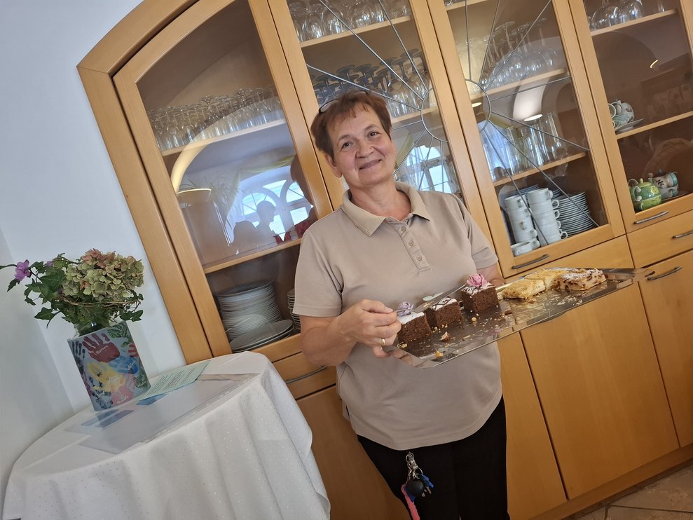 Eine Dame hält ein Tablett mit Kuchen