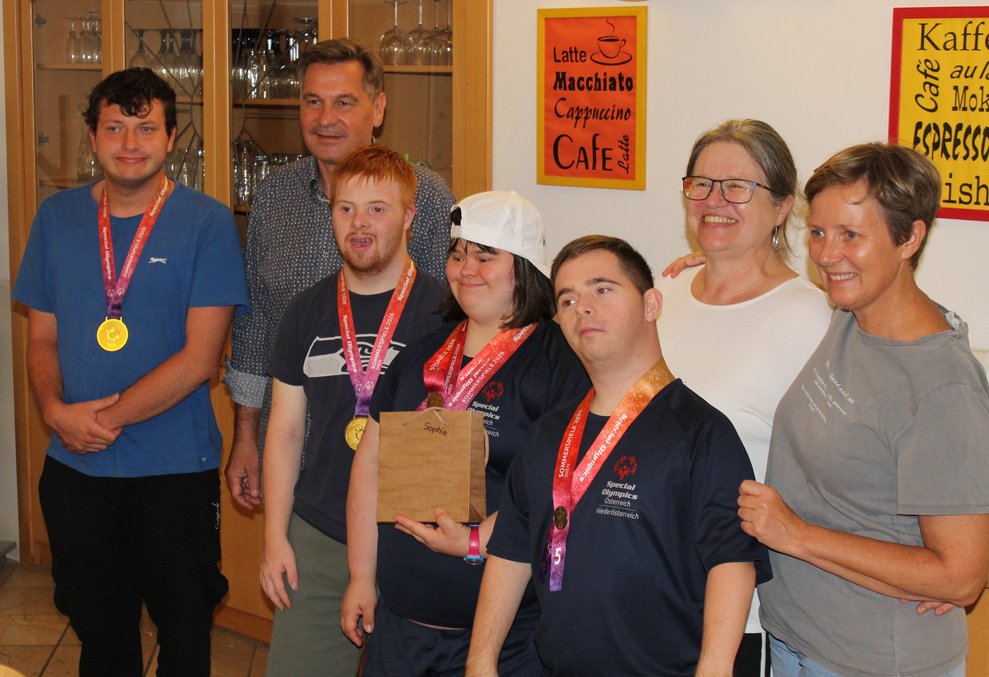 Drei Herren und eine Dame haben eine Medaille umgehängt und stehen mit vier anderen Personen für ein Foto zusammen