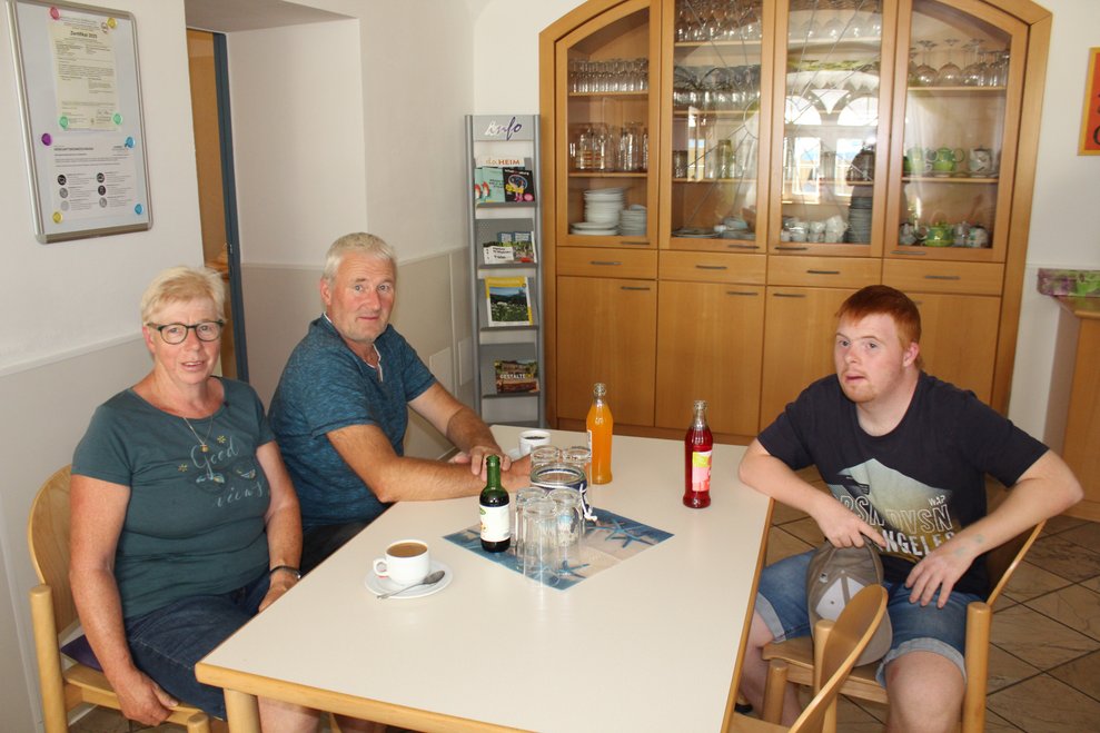 Drei Personen sitzen an einem Tisch.