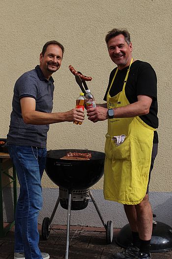 Zwei Männer stehen bei einem Griller