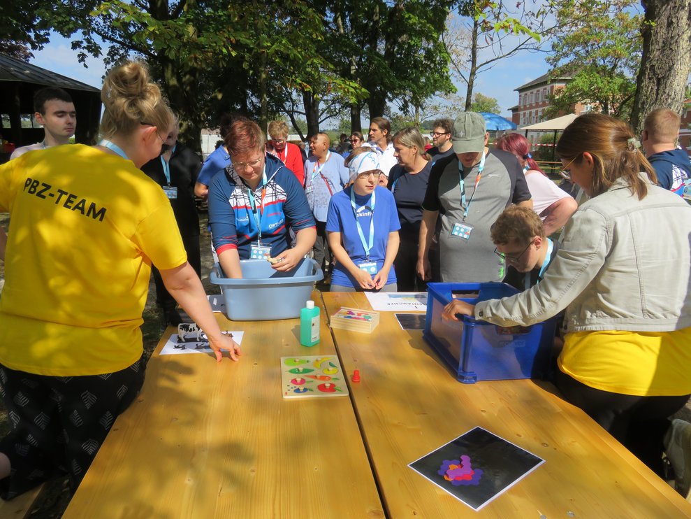 Zwei Personen machen mit bei einem Spiel wo man in einen perlengefüllten Behälter greift.