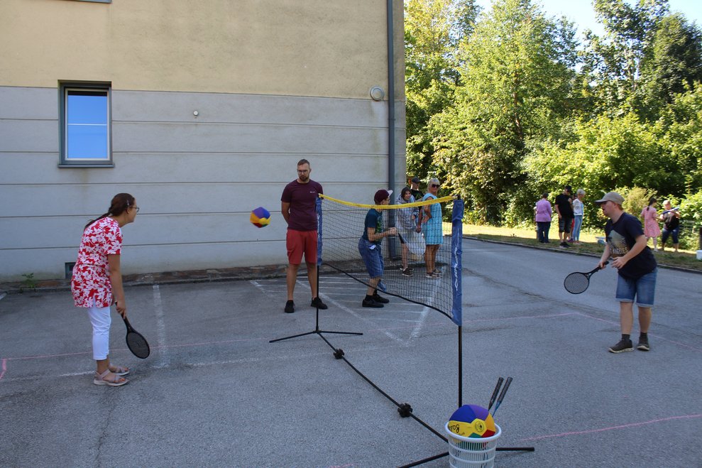 Zwei Personen spielen Ball übers Netz mit Schlägern.